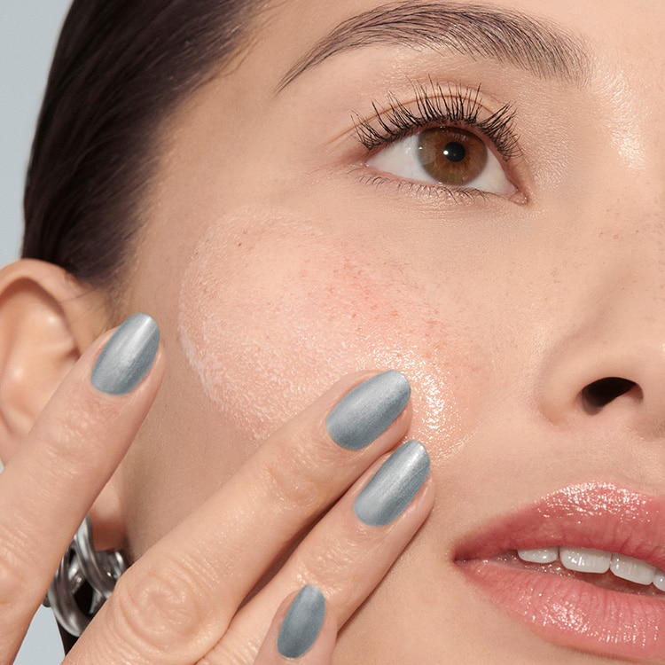 Model applying Skin Long-Wear Weightless Foundation to skin with a foundation brush